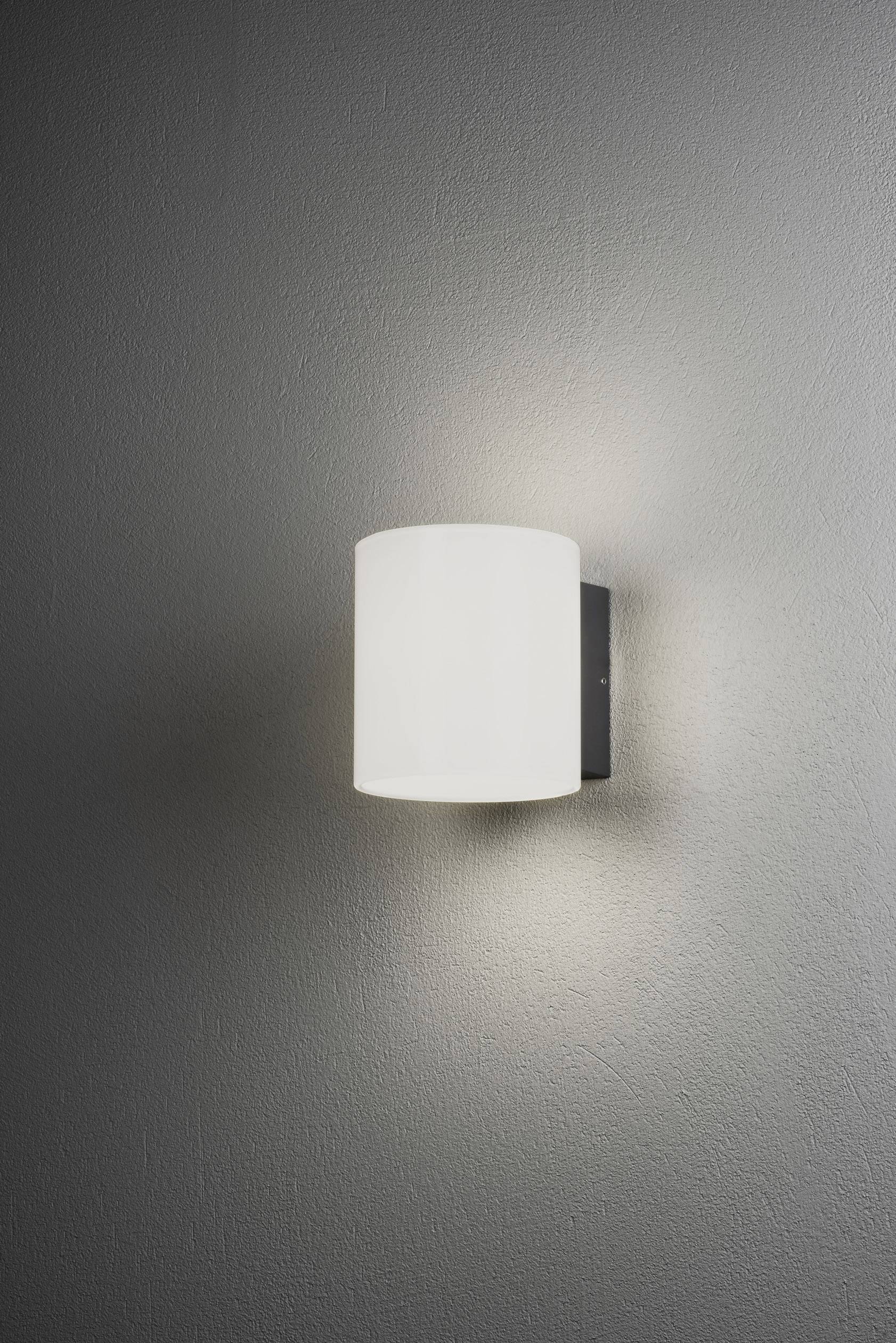 Eine moderne weiße Wandlampe leuchtet an einer grauen Wand und erzeugt ein sanftes, gleichmäßiges Licht.