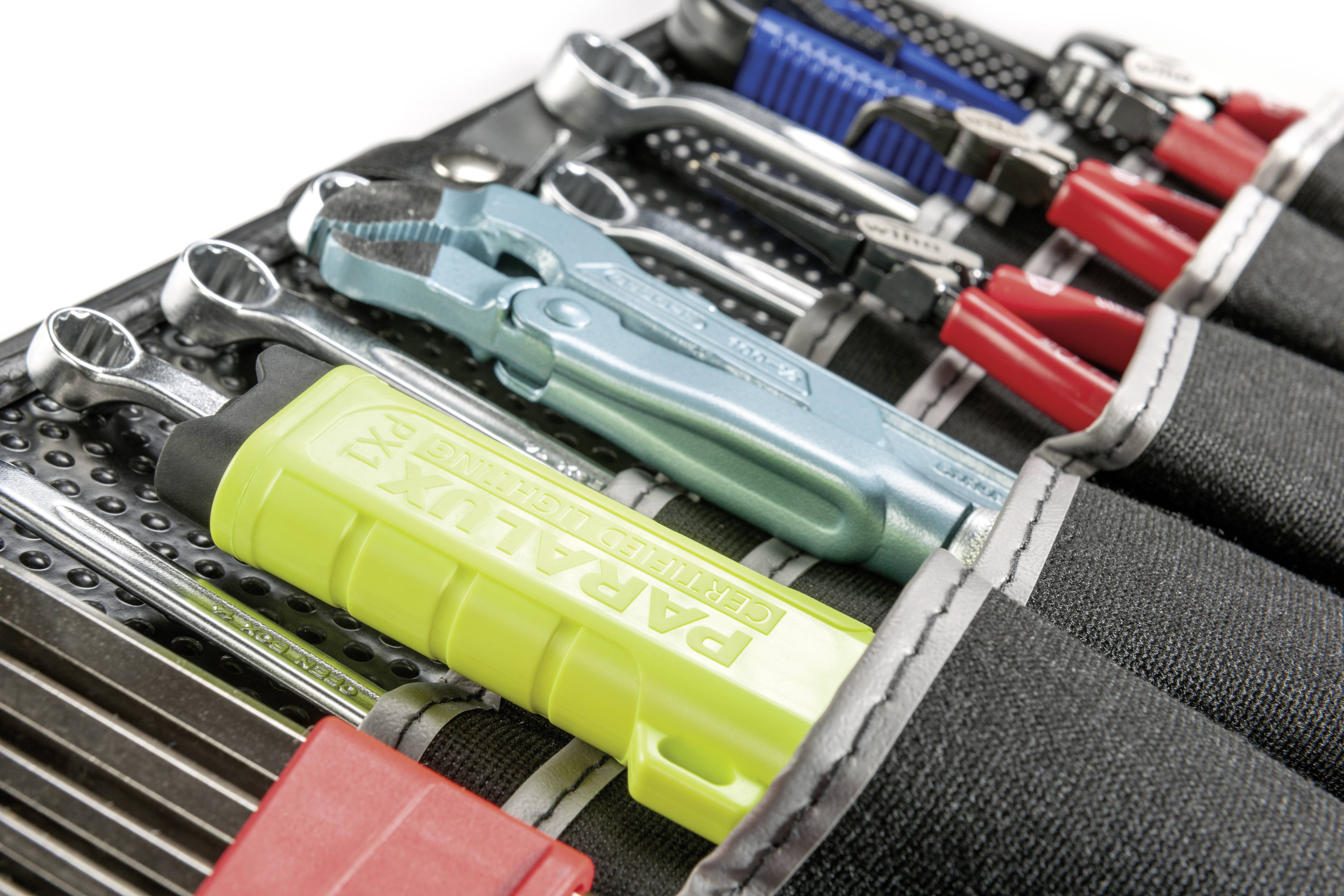 Ein Set von verschiedenen Handwerkzeugen, darunter Schraubenschlüssel, Zangen und ein grüner Griff, in einer Werkzeugtasche organisiert.