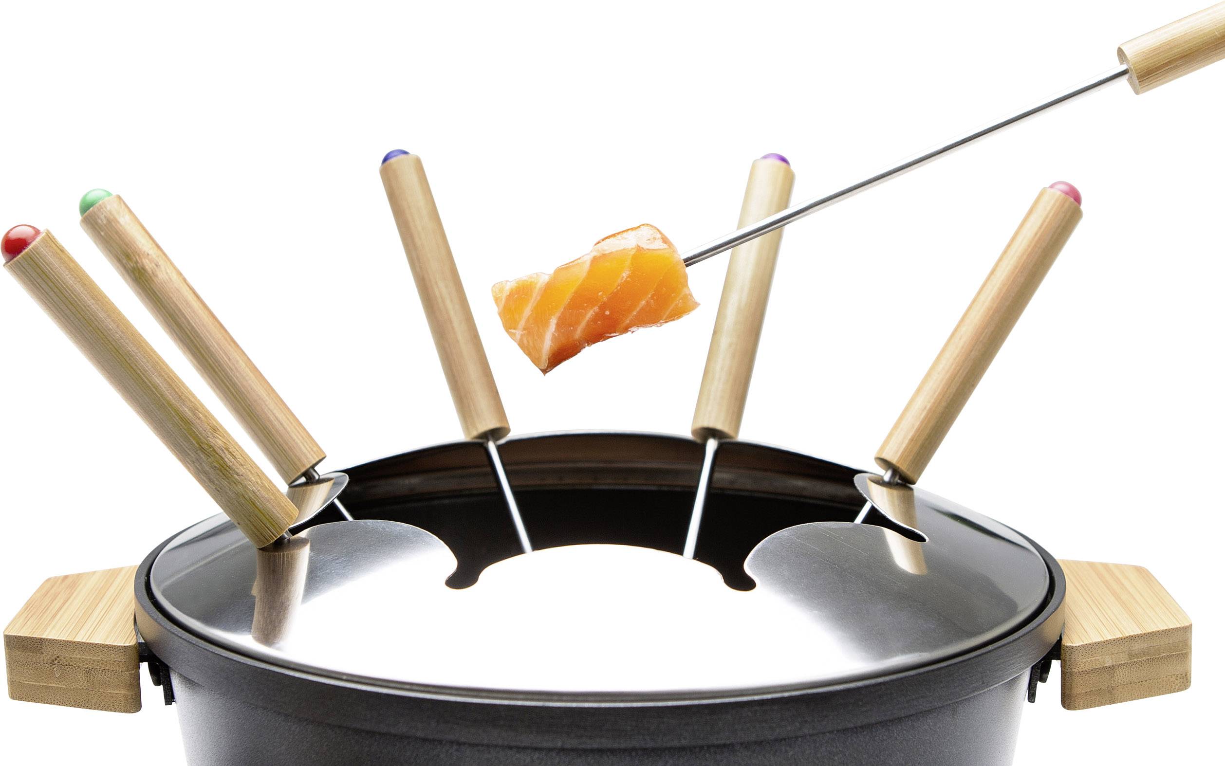 Fondue-Set mit vier Gabeln, eine mit einem Lachsstück oberhalb des Topfs. Die Gabeln haben farbige Enden. Hauptgerichtszene.