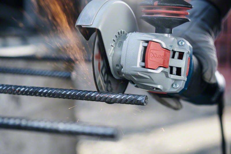 Eine Person schneidet mit einer elektrischen Trennschleifmaschine Metallstäbe. Funken fliegen vom Kontaktpunkt des Geräts.