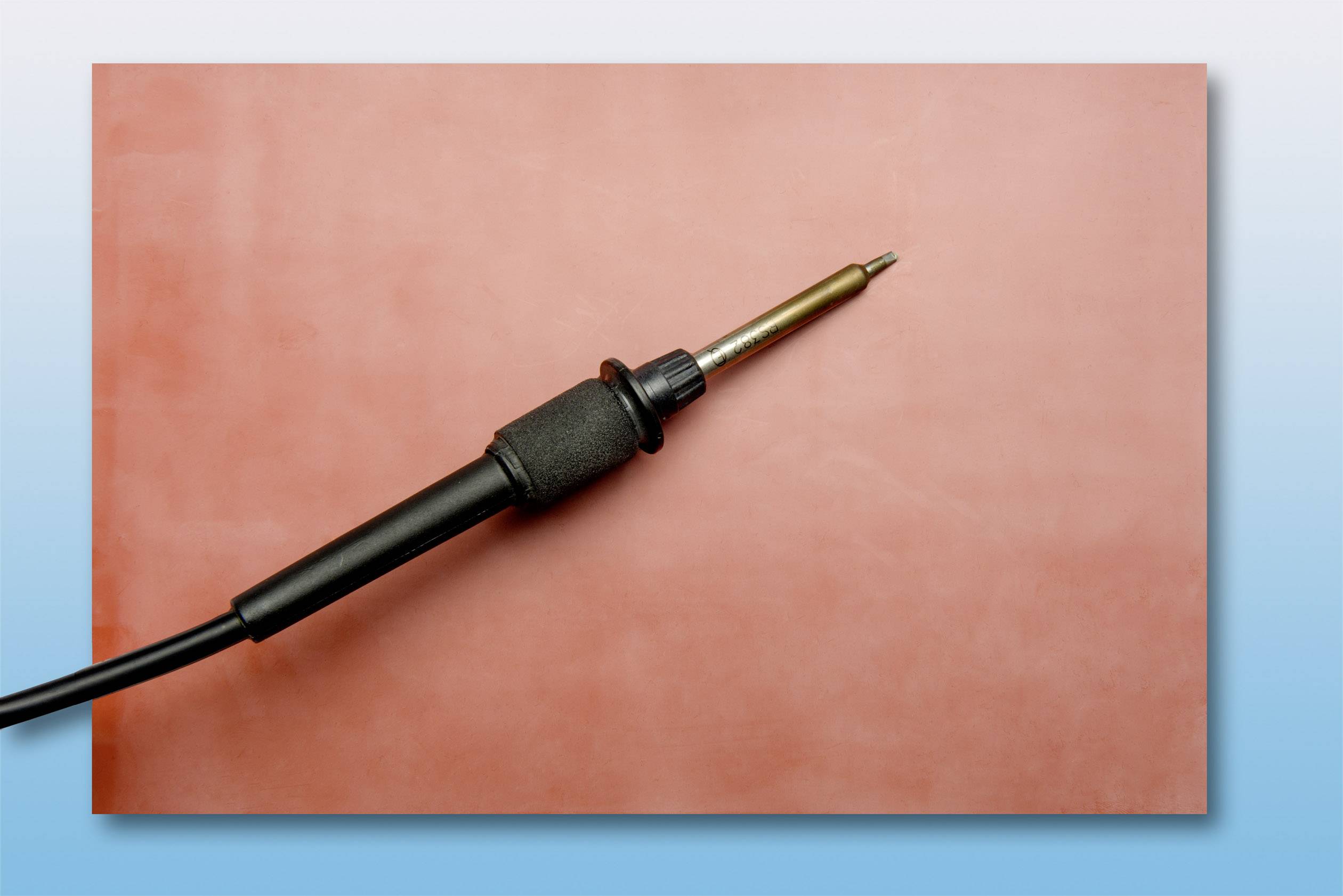 Ein Lötkolben liegt auf einer rot-blauen Fläche.