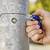 Eine Hand zeigt einen blauen und roten Werkzeugsatz, der auf einen Schraubenkopf an einem Metallpfosten gerichtet ist, als ob repariert wird.