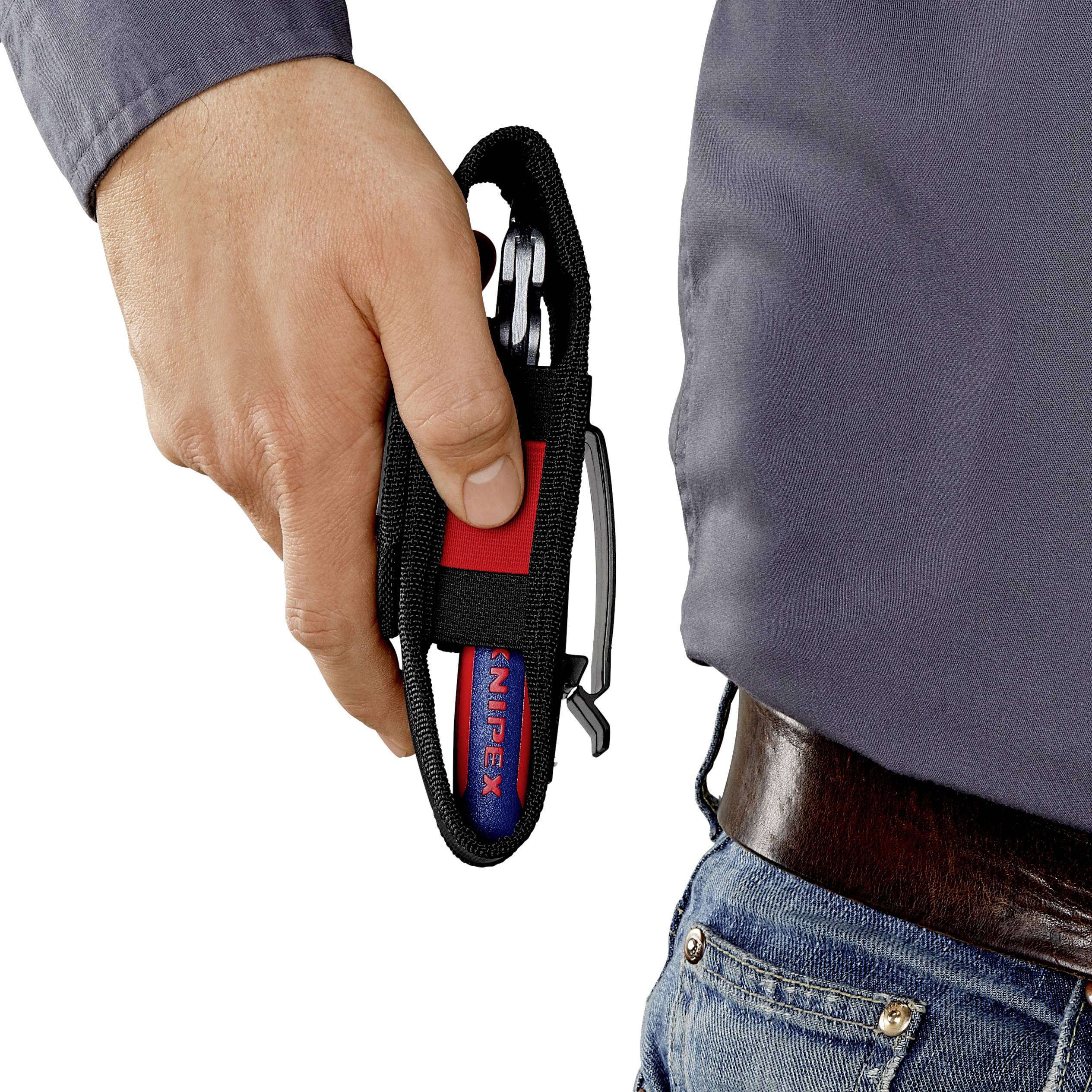 Eine Hand hält einen roten Karabinerhaken, der an einer Gürtelschlaufe befestigt ist. Der Karabiner hat einen Schlüsselring.