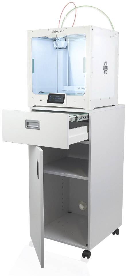 3D-Drucker auf einem Schrank mit Schublade und öffnender Tür unten. Oben befinden sich Kabel, die in das Gerät führen.