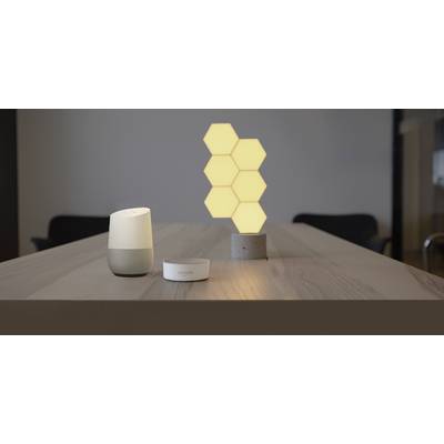 Ein Tisch mit einem Smart-Lautsprecher, einem intelligenten Assistenten und leuchtenden sechseckigen Lichtern im Hintergrund.