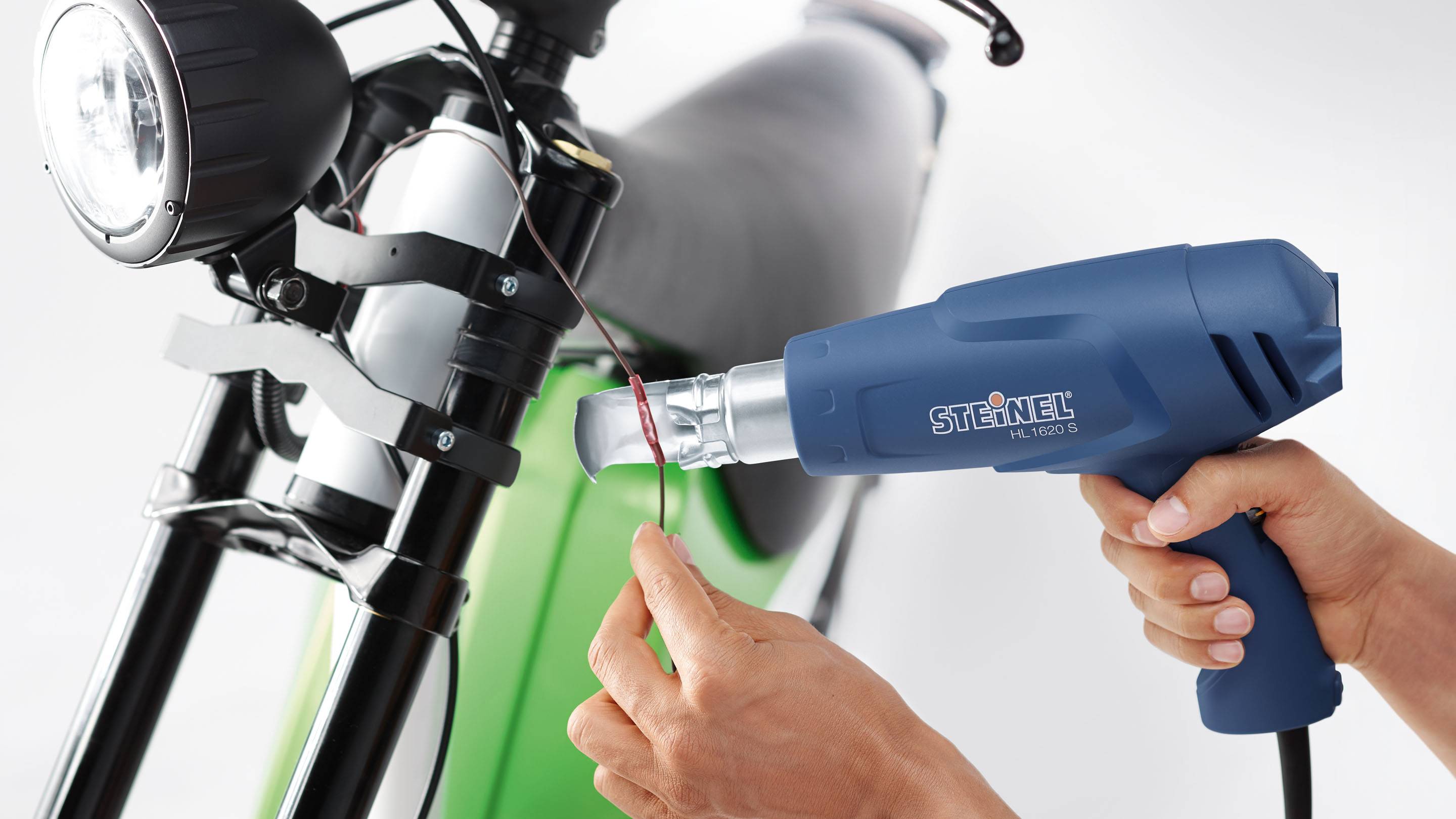 Eine Person nutzt ein Heißluftgebläse, um ein Kabel an einem Fahrradrahmen anzubringen.