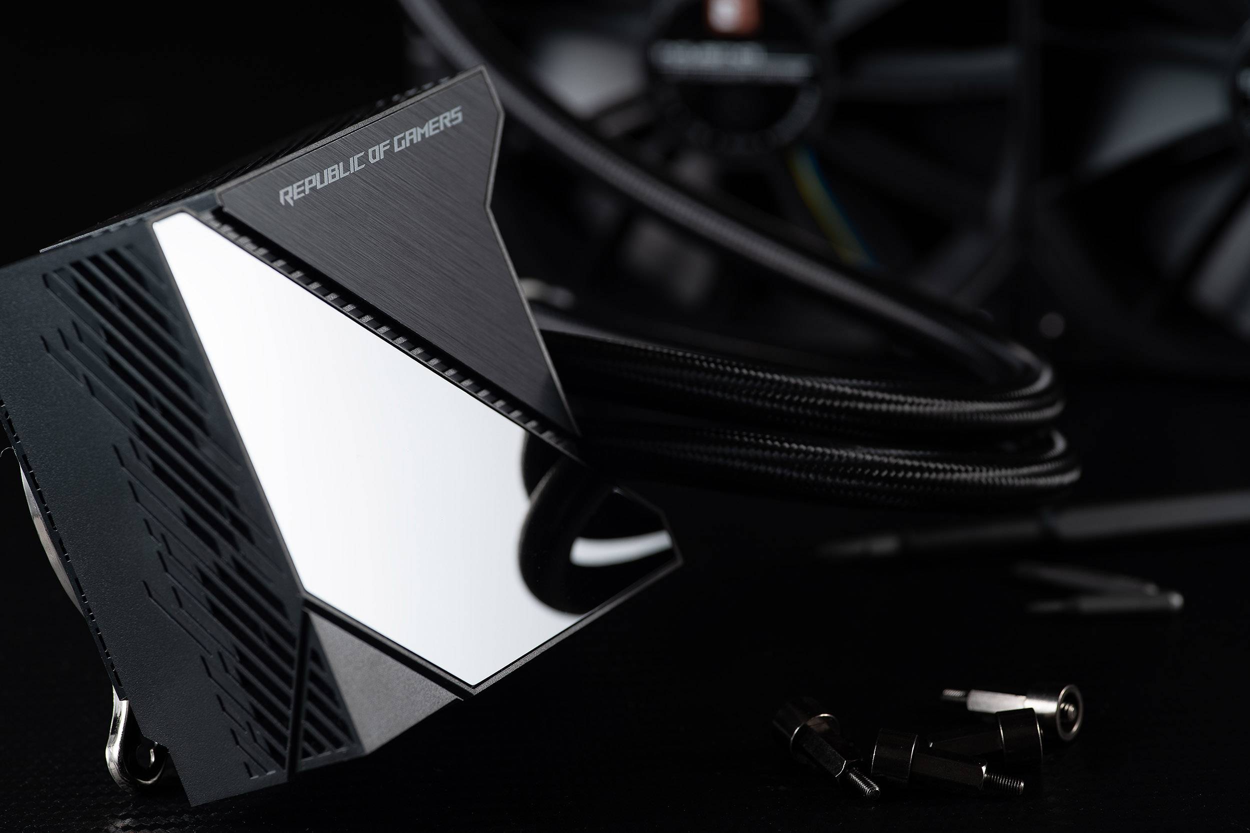 PC-Kühlerset mit Metalloberfläche und Kabel. Schriftzug 'Republic of Gamers'. Im Hintergrund sind Lüfterblätter teils sichtbar.