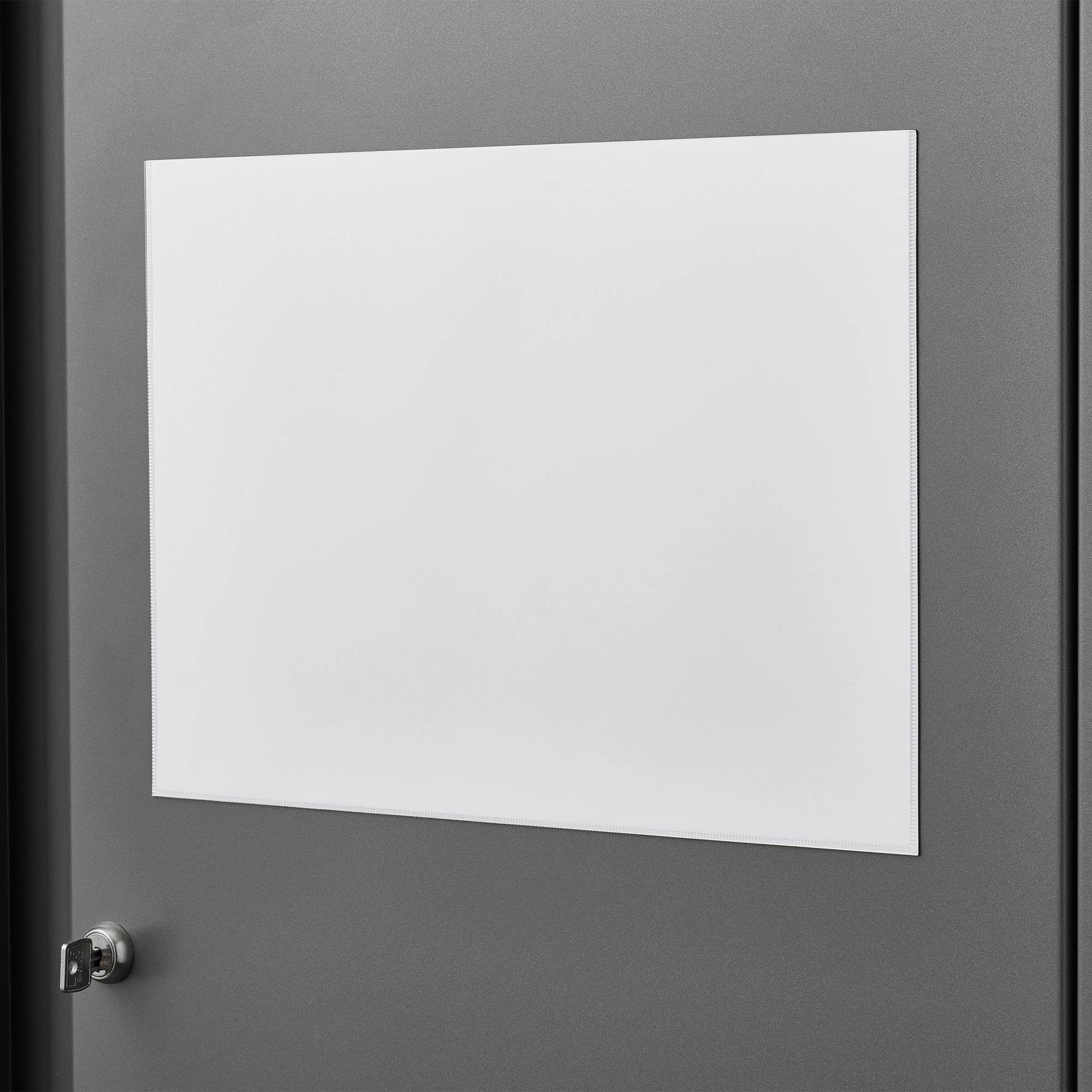 Eine weiße, leere Tafel hängt an einer grauen Tür mit einem Türgriff links, bereit für Notizen oder Ankündigungen.