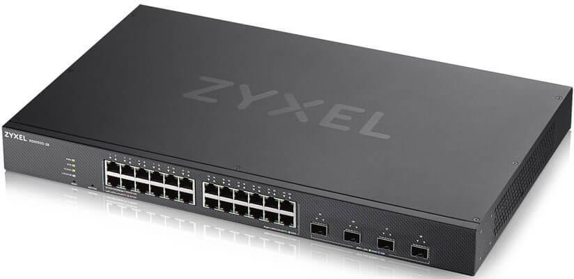 Ein schwarzer Netzwerk-Switch von Zyxel mit 24 Ethernet-Ports und 4 SFP-Ports, auf einem Tisch liegend.