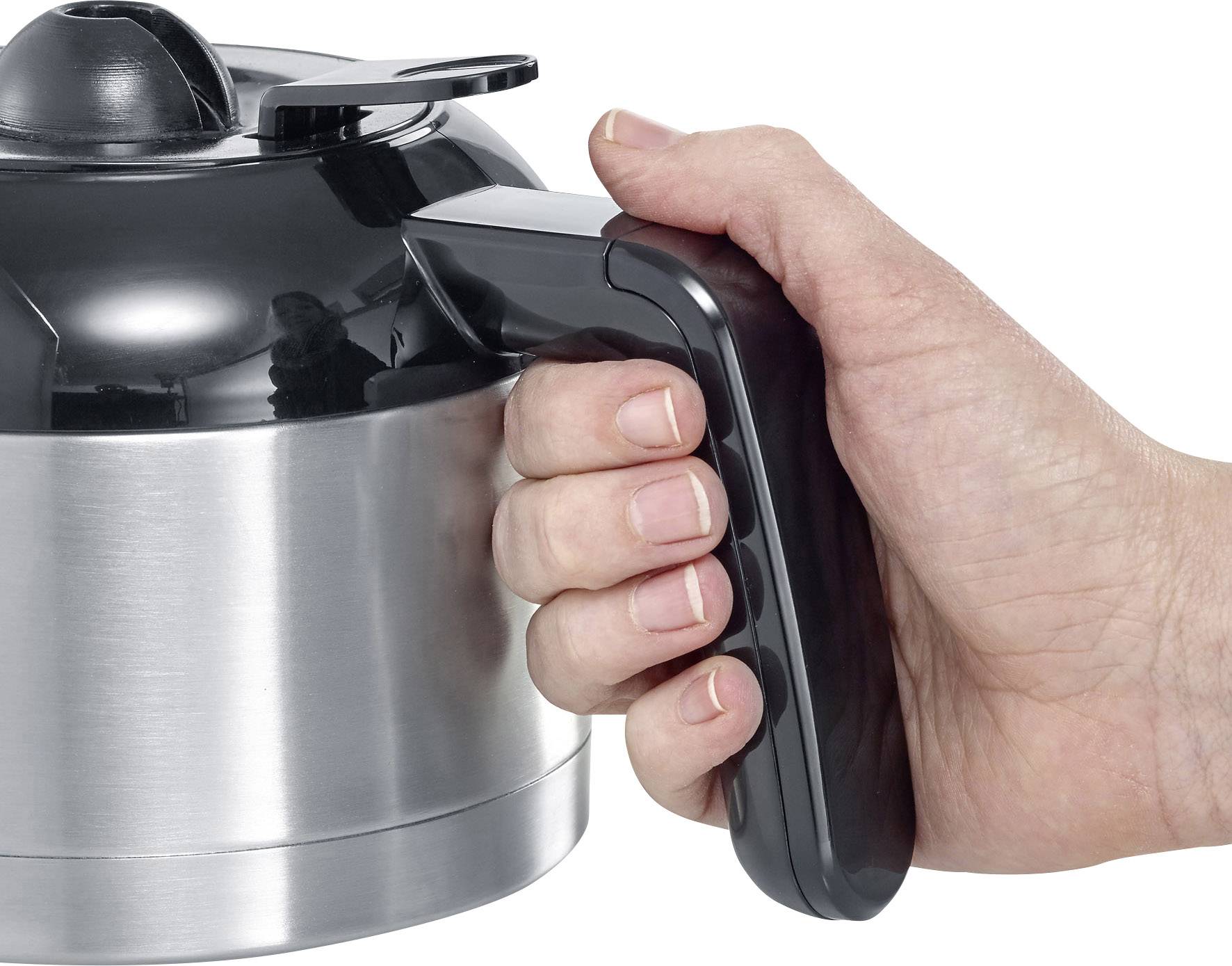 Eine Hand hält einen schwarzen Griff einer silbernen Kaffeekanne.
