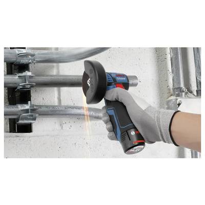 Behandschuhte Hand, die ein kabelloses Elektrowerkzeug mit einer Schneidscheibe an einem Metallrohr verwendet, wobei Funken in einem industriellen Arbeitsbereich entstehen.