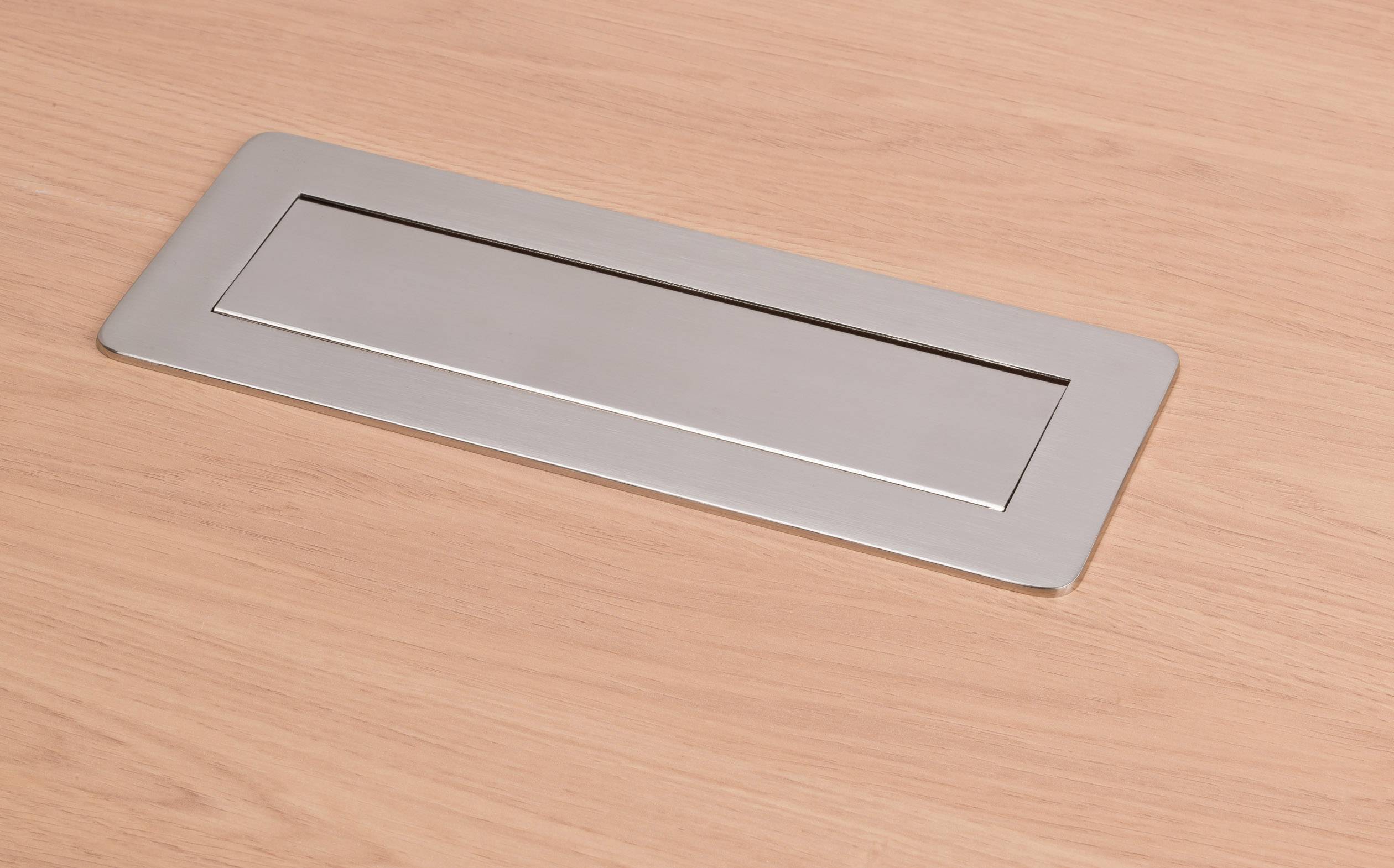 Metallische Kabeldurchführung auf einem Holztisch, geschlossen.