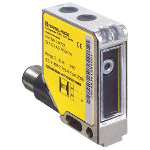 Ein rechteckiger, industrieller Sensor von Pepperl+Fuchs mit gelbem Etikett. Seriennummer und technische Spezifikationen sind sichtbar.