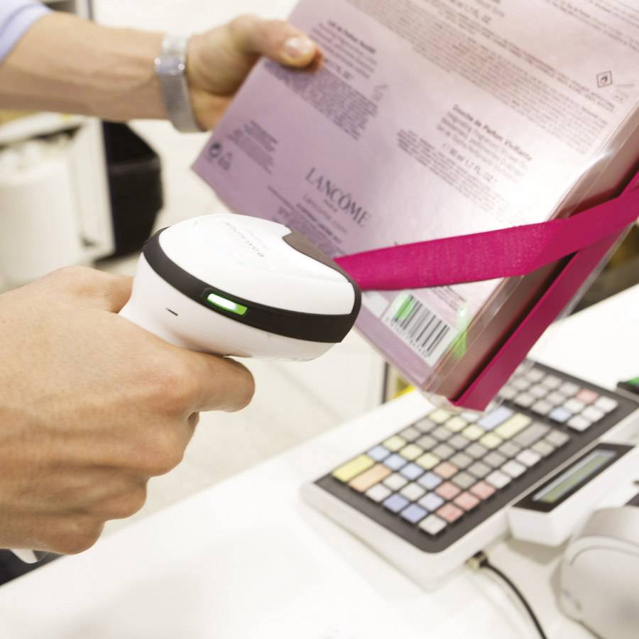 Eine Person scannt mit einem Barcode-Scanner eine Produktverpackung an der Kasse eines Geschäfts.