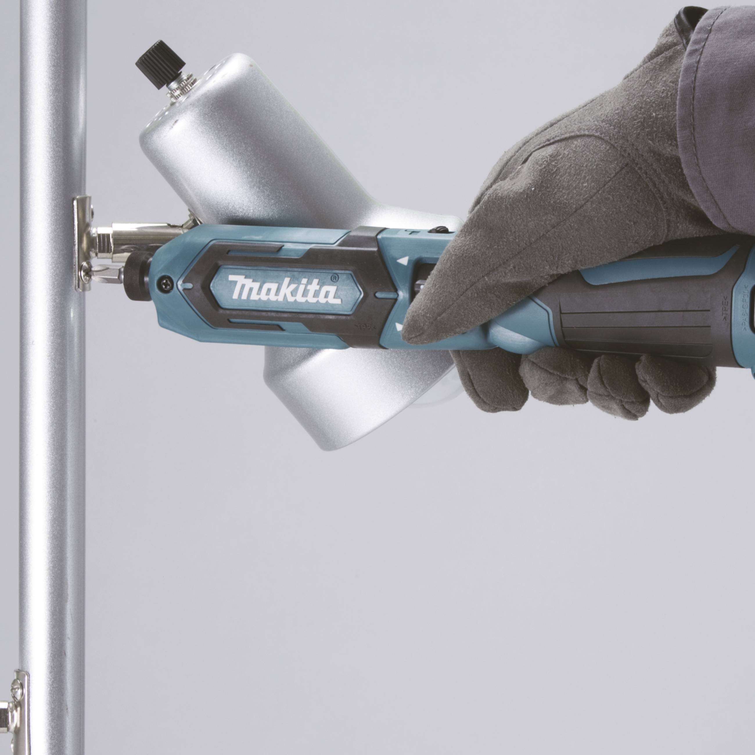 Eine behandschuhte Hand hält ein elektrisches Werkzeug von Makita und befestigt eine Schraube an einem Metallrohr.