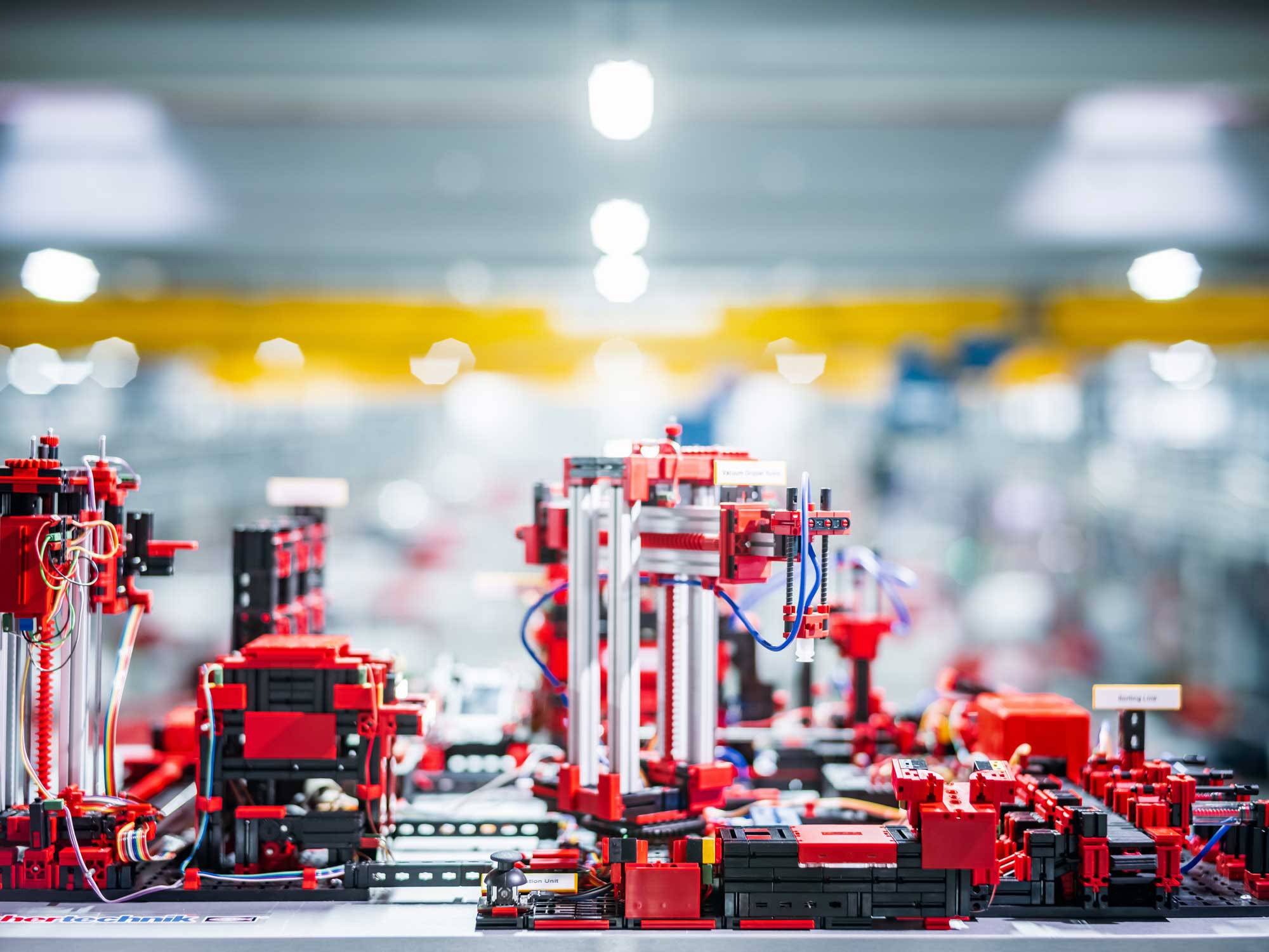 Industrie-Roboter in einer Fabrik montieren Präzisionsteile mit rotem und schwarzem Equipment auf einem unscharfen Hintergrund.