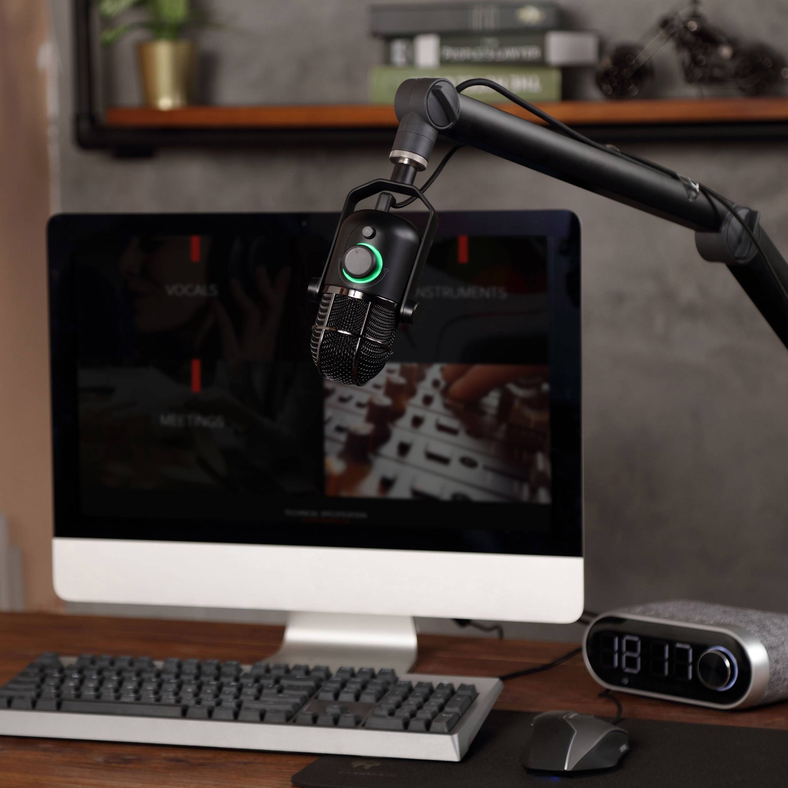 'Mikrofon auf einem Ständer vor einem Computer in einem modernen Arbeitszimmer, bereit für Podcasts oder Online-Meetings.'