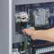 Eine Hand repariert einen elektrischen Schaltschrank mit einem Schraubendreher. Verschiedene Kabel und Schaltgeräte sind sichtbar.