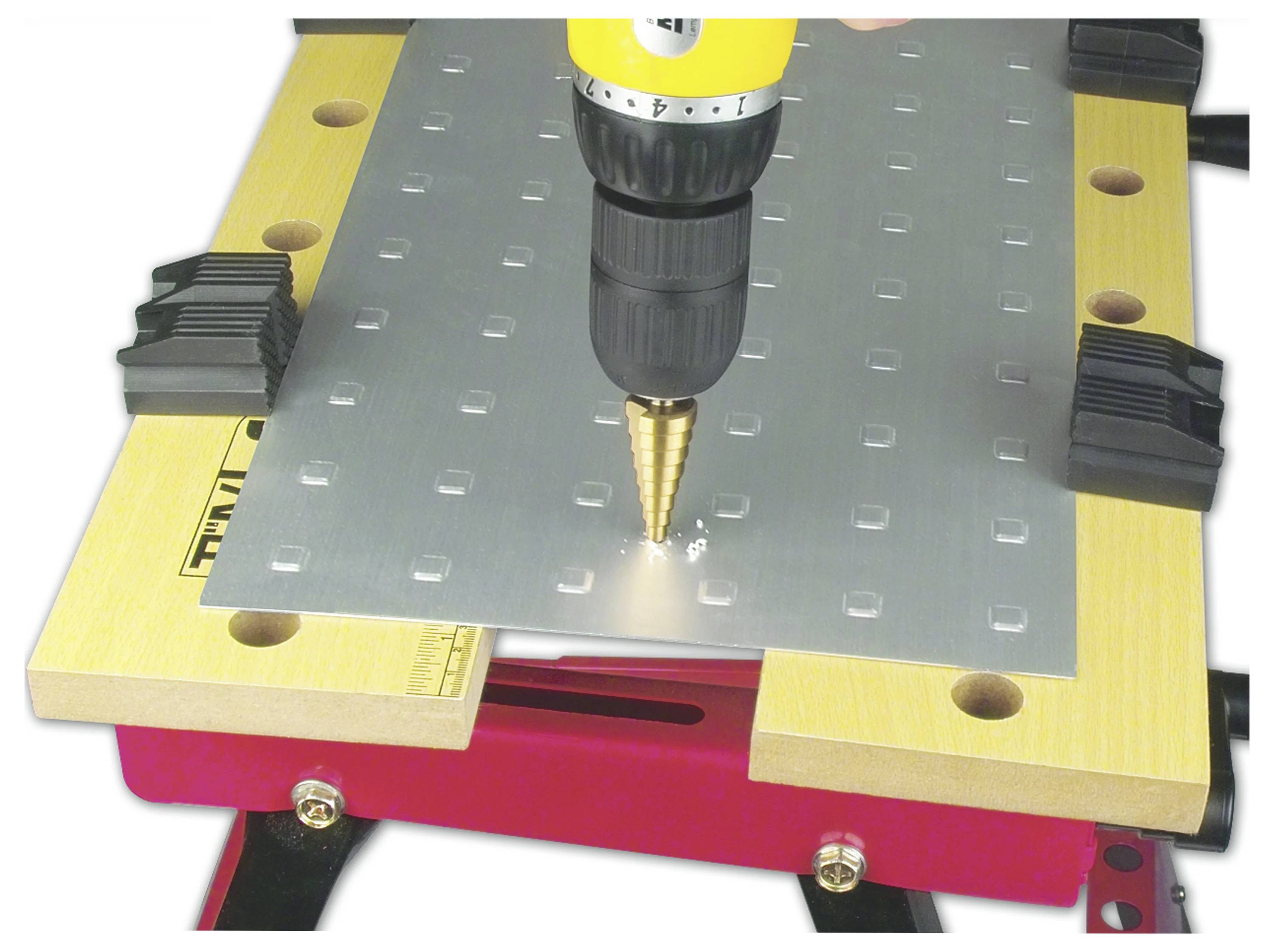 Eine Bohrmaschine mit einem Stufenbohrer bohrt ein Loch in ein auf einer Werkbank befestigtes Metallblech und hebt dabei die in der Werkstatt verwendeten Werkzeuge hervor.