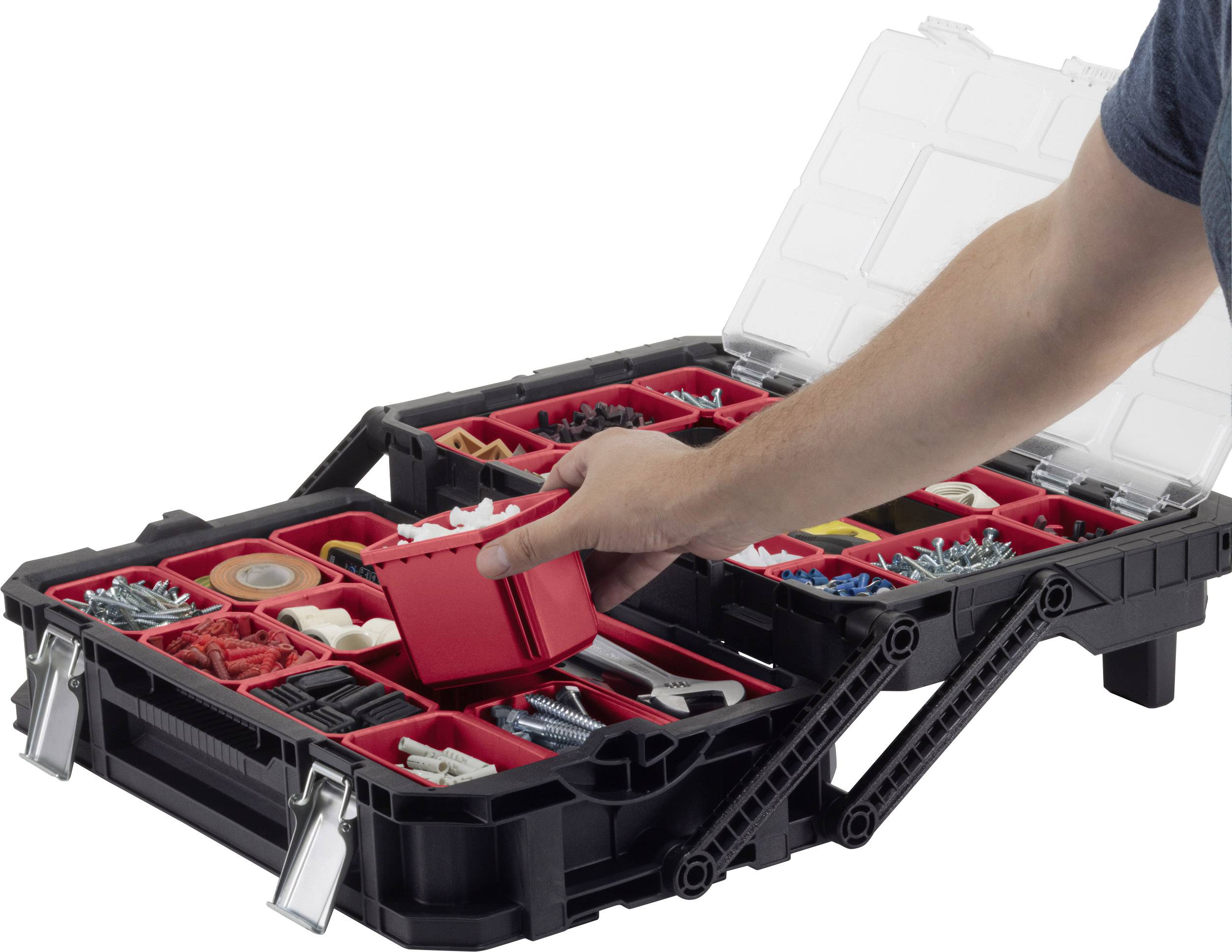 Ein geöffneter Werkzeugkoffer mit verschiedenen Fächern, die Schrauben, Dübel und Werkzeuge enthalten. Eine Hand greift ein rotes Fach.
