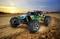 Spielzeug-Geländewagen fährt schnell über eine sandige Offroad-Strecke bei Sonnenuntergang, Reifen wirbeln Sand auf.