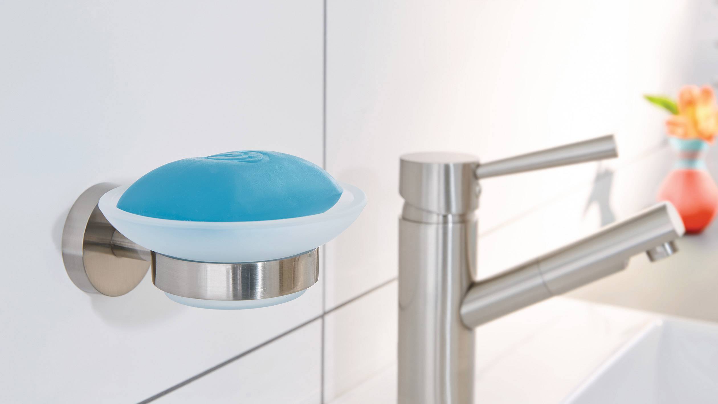 Seifenschale mit blauer Seife hängt an einer Wand über einem modernen Wasserhahn neben einem hellen Waschbecken.