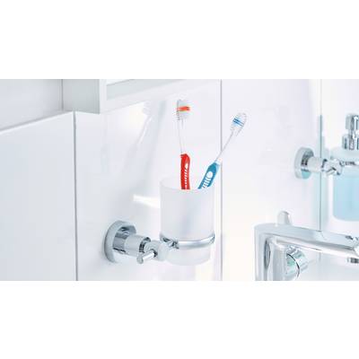 Zwei Zahnbürsten, eine rot-weiße und eine blau-weiße, stehen in einem weißen Wandbecher im Badezimmer neben einem Wasserhahn.