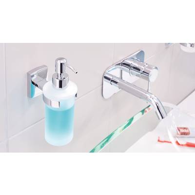 Seifenspender mit blauem Flüssigseife an gefliester Wand neben glänzendem Wasserhahn in moderner Badezimmerumgebung.