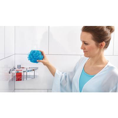 Frau in blauem Bademantel hält einen blauen Duschschwamm in einem gefliesten Badezimmer.