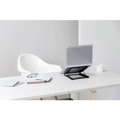 Ein weißer Schreibtisch mit einem Laptop auf einem Ständer, Notizbüchern, einer Brille und einer Tasse; daneben steht ein weißer Stuhl.