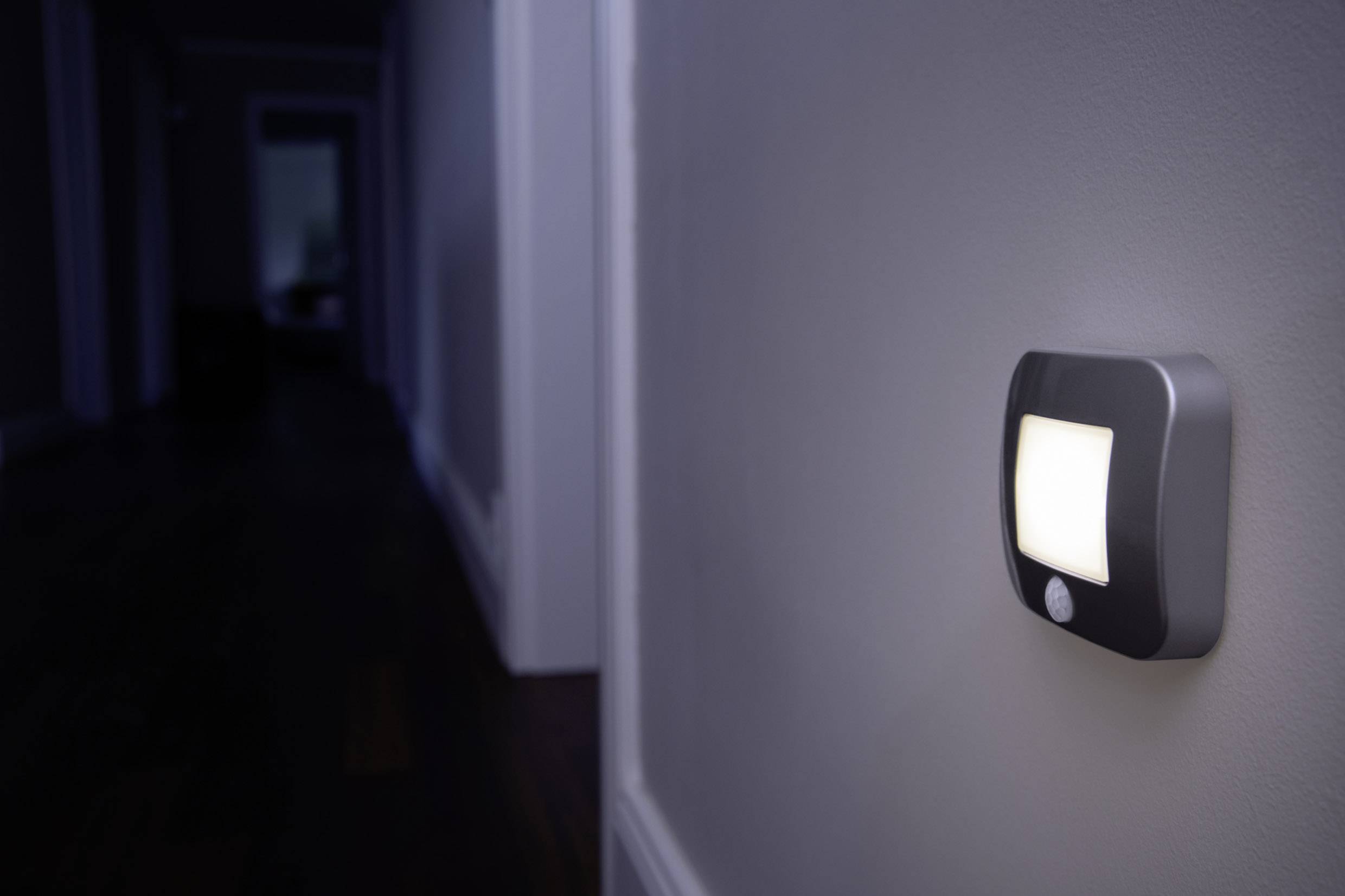 Ein Nachtlicht leuchtet in einem dunklen Flur und ist an der Wand montiert, um den Weg dezent zu beleuchten.