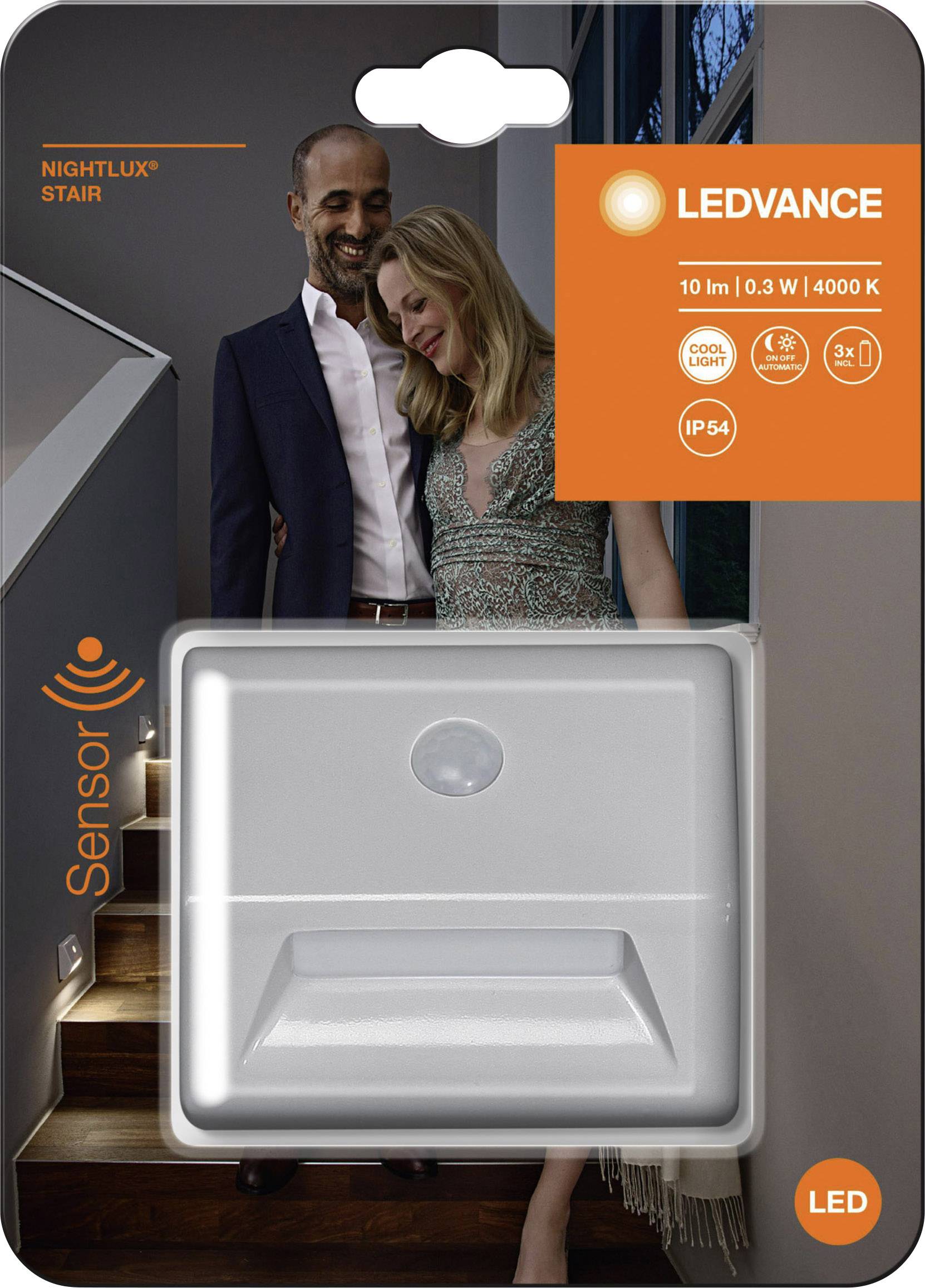 Paar steht lächelnd nah beieinander auf einer Treppe. Vor ihnen eine LED-Leuchte mit Bewegungssensor auf der Verpackung abgebildet.