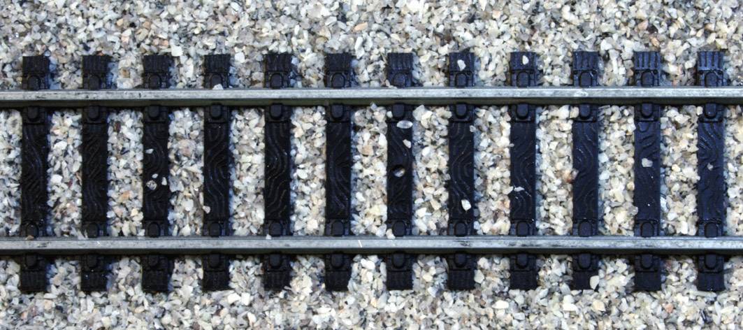 Gleisstück auf einem Schotterbett, das Teil eines Eisenbahngleissystems darstellt.