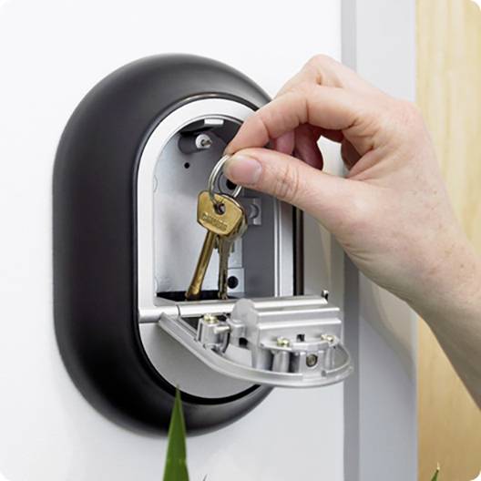 Hand öffnet einen Wand-Schlüsselkasten mit einem Schlüsselbund.