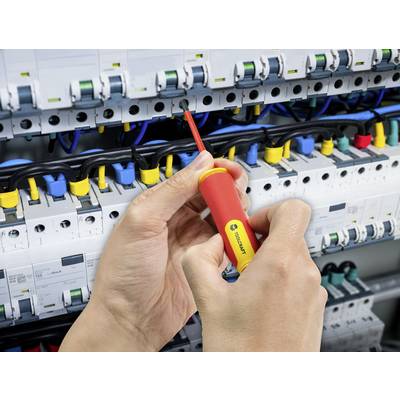 Eine Person benutzt einen Schraubendreher, um an einer elektrischen Schalttafel Kabel anzuschließen. Verschiedene farbige Kabel sind sichtbar.