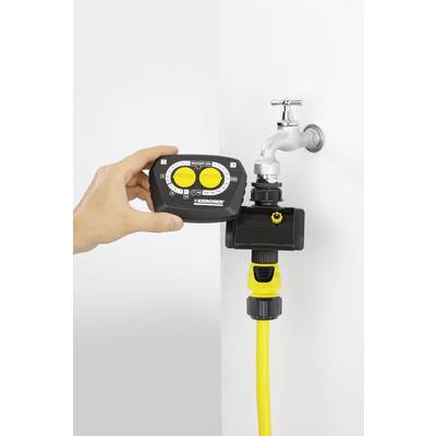 Eine Hand hält ein Bewässerungssteuergerät vor einem Wasserhahn mit gelbem Schlauchanschluss, bereit zur Installation.