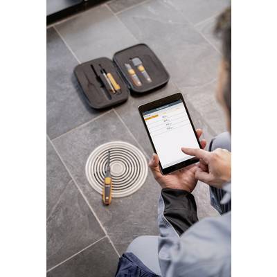 Eine Person bedient ein Tablet zur Messung von Daten, daneben liegt Werkzeug auf einem Bodenablauf.