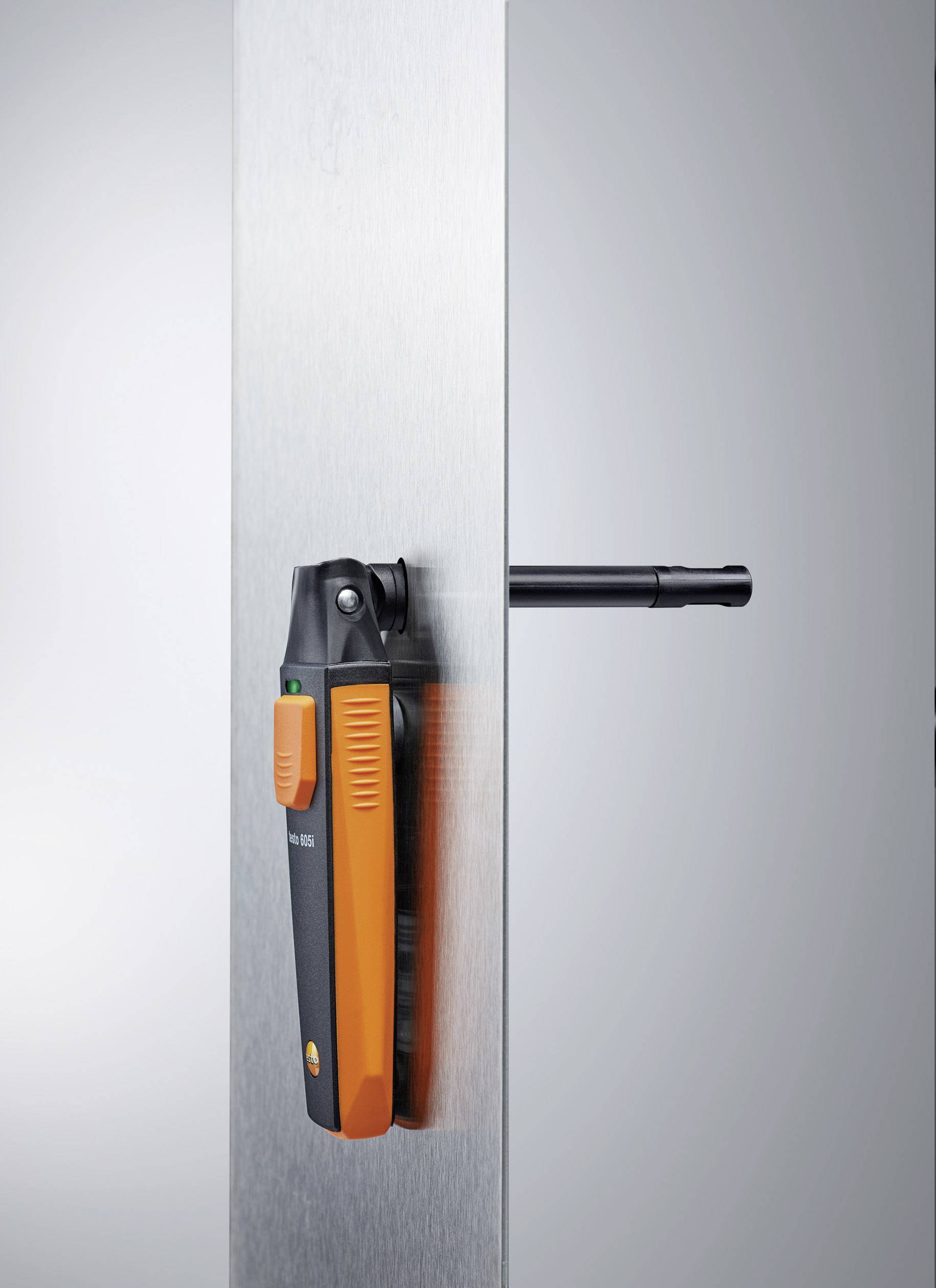 Ein orange-schwarzes digitales Gerät, horizontal montiert an einer vertikalen Metalloberfläche, zeigt präzise Positionierung.