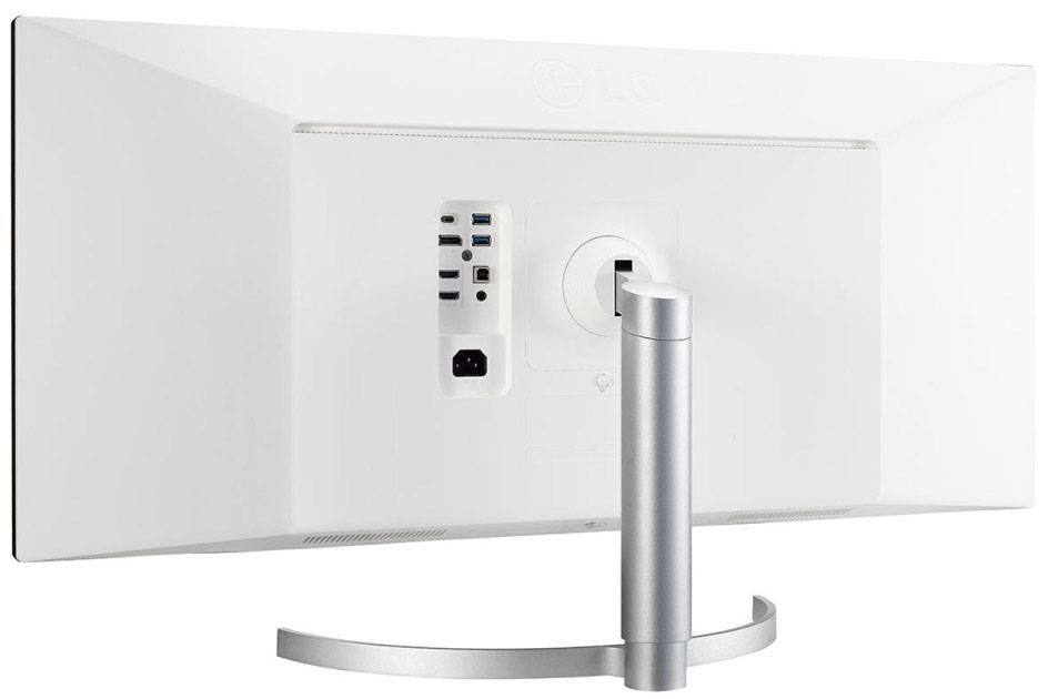 Ein weißer Computermonitor von hinten mit mehreren Anschlussmöglichkeiten, steht auf einem metallischen, halbkreisförmigen Ständer.