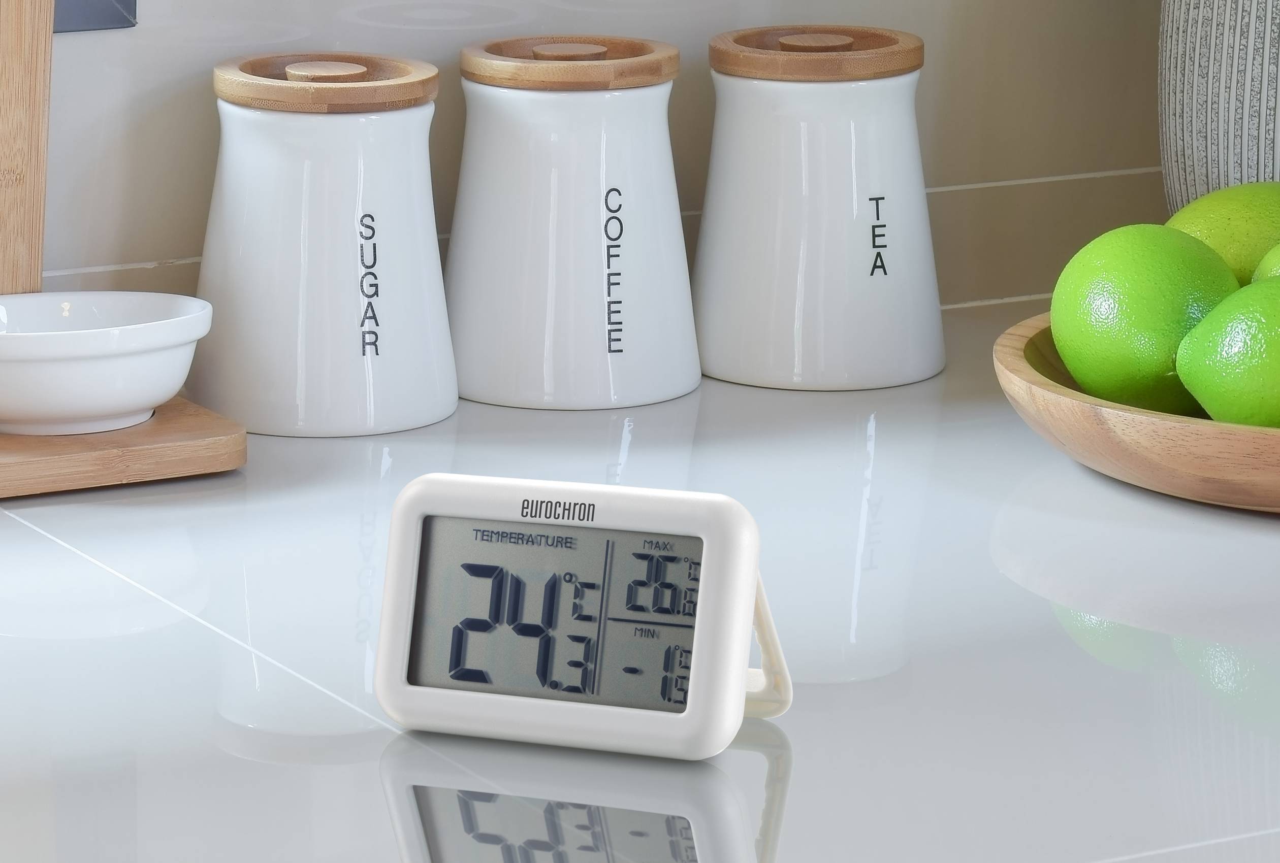 Ein Digitalthermometer zeigt 24,5°C Innentemperatur und 26,8°C Außentemperatur an. Daneben stehen Gefäße für Zucker, Kaffee und Tee.
