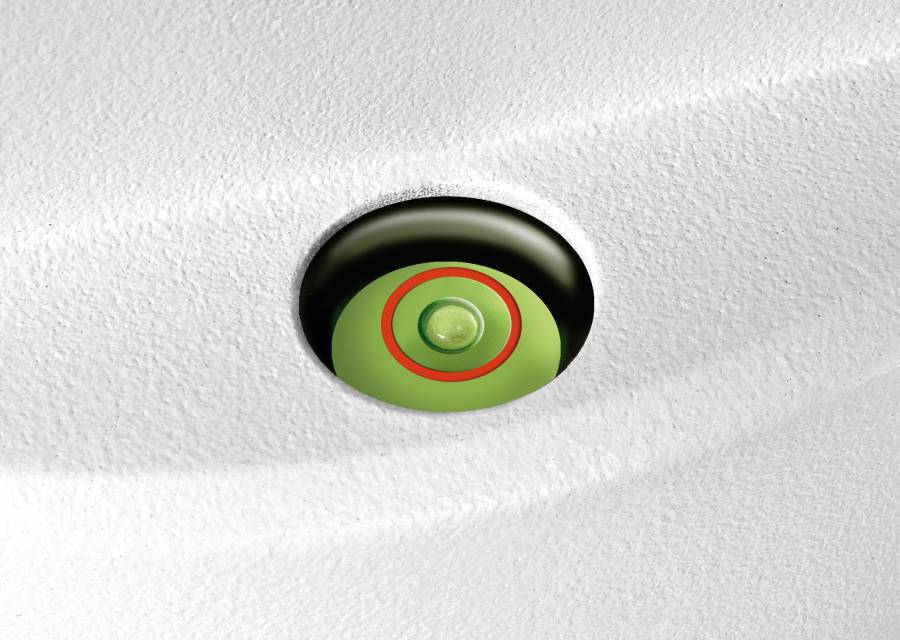 Eine grüne, kreisförmige Taste ist in einer weißen, strukturierten Oberfläche eingelassen. Sie ist von einem roten Ring umgeben.