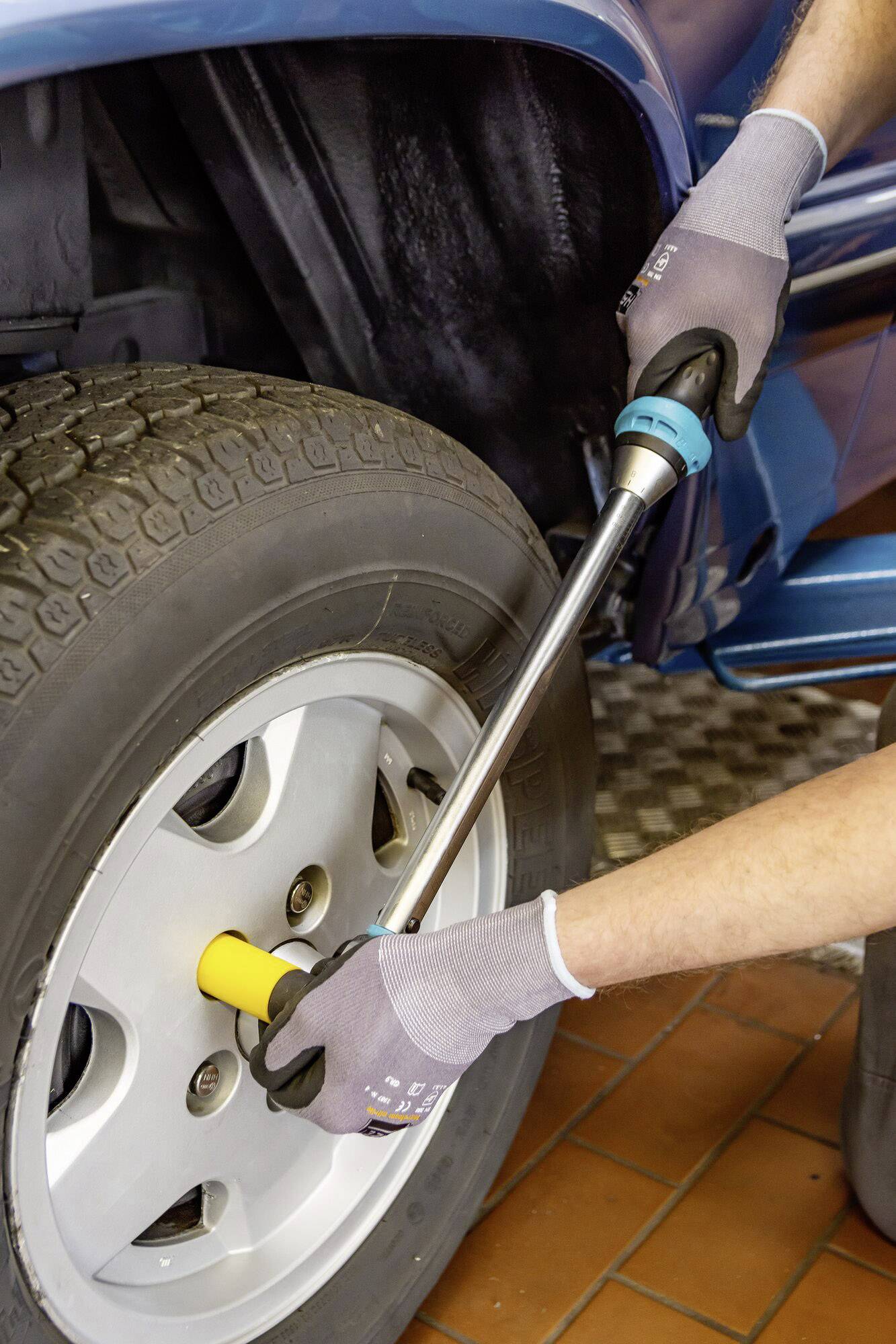 Eine Person zieht mit einem Drehmomentschlüssel die Radmuttern eines Autos an, um die Felge sicher zu befestigen.