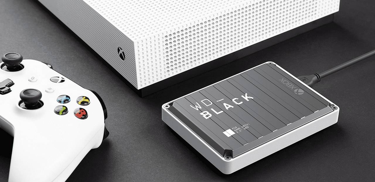 'Externe WD Black Festplatte' verbunden mit einer weißen Spielekonsole und einem Controller. Geräte auf schwarzem Hintergrund.