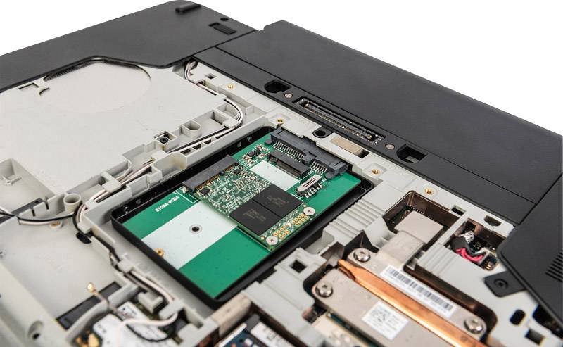 Ein Laptop mit geöffneter Unterseite zeigt den Einbau von Computerhardware-Komponenten wie RAM und Festplatte.