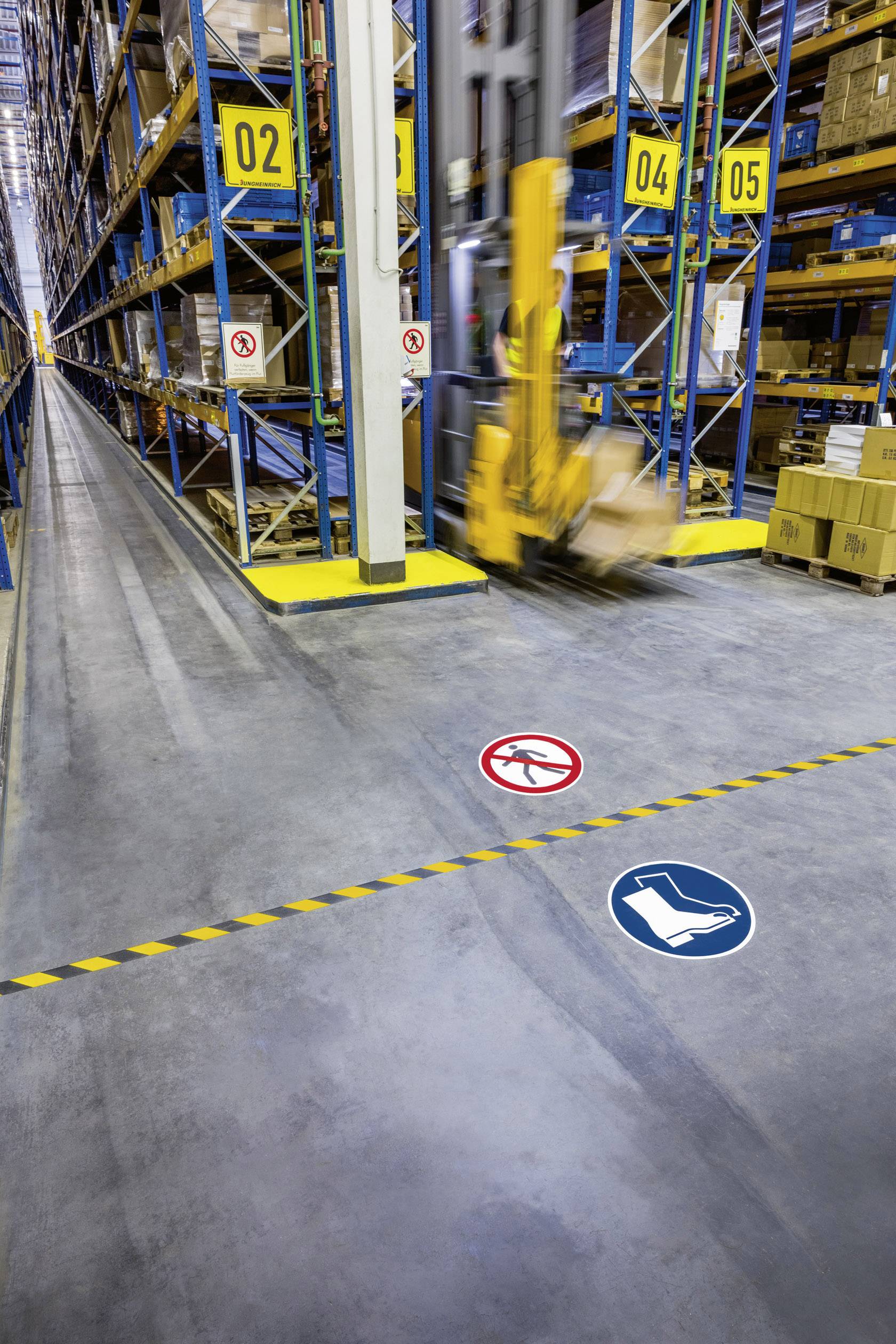 Ein Gabelstapler bewegt sich in einem Lagerhausgang. Schilder auf dem Boden weisen auf Sicherheitsvorschriften hin. Regale sind voll mit Kartons.