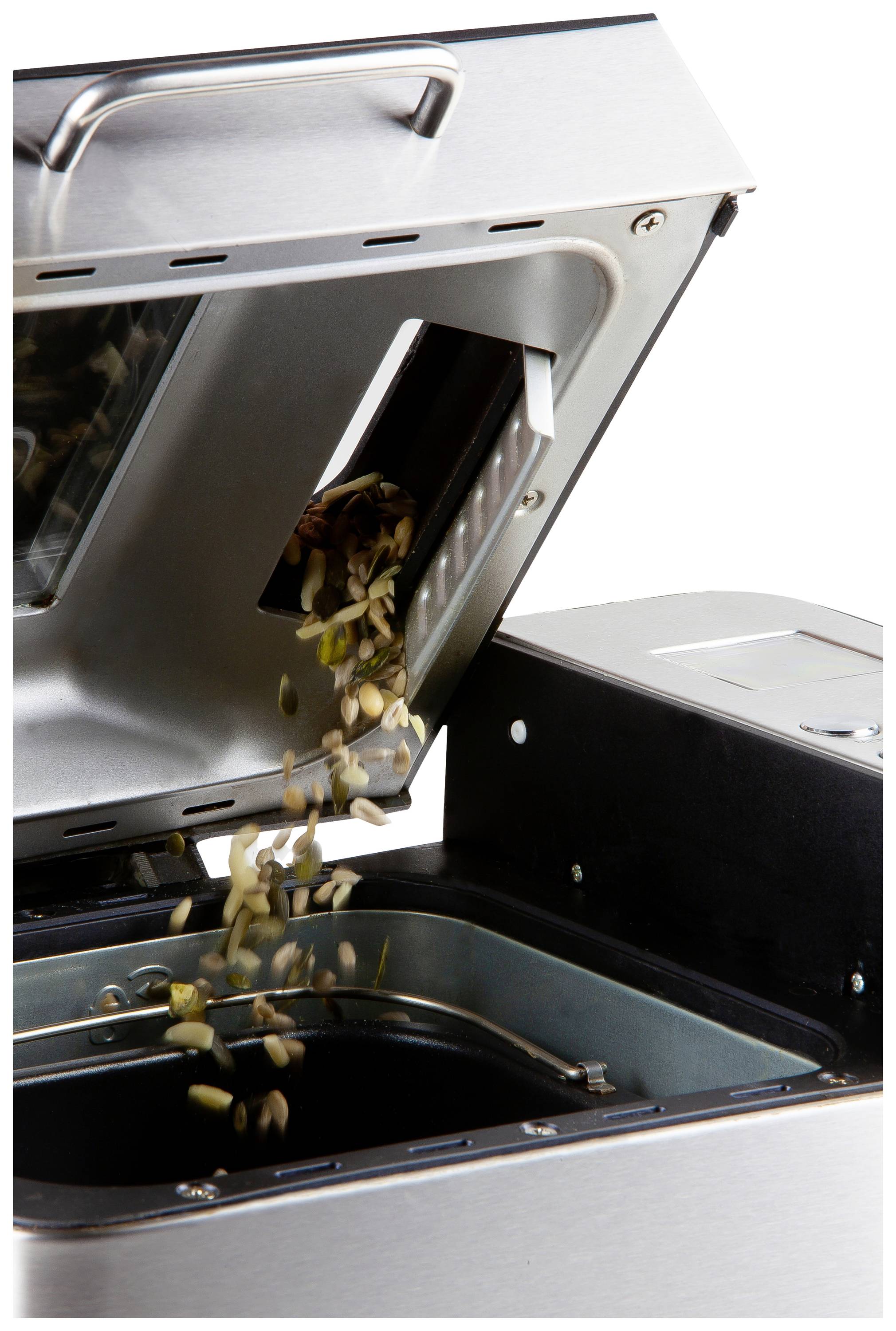 Ein Brotbackautomat, bei dem Samen und Körner aus einem kleinen Fach in den Teigbehälter rieseln.