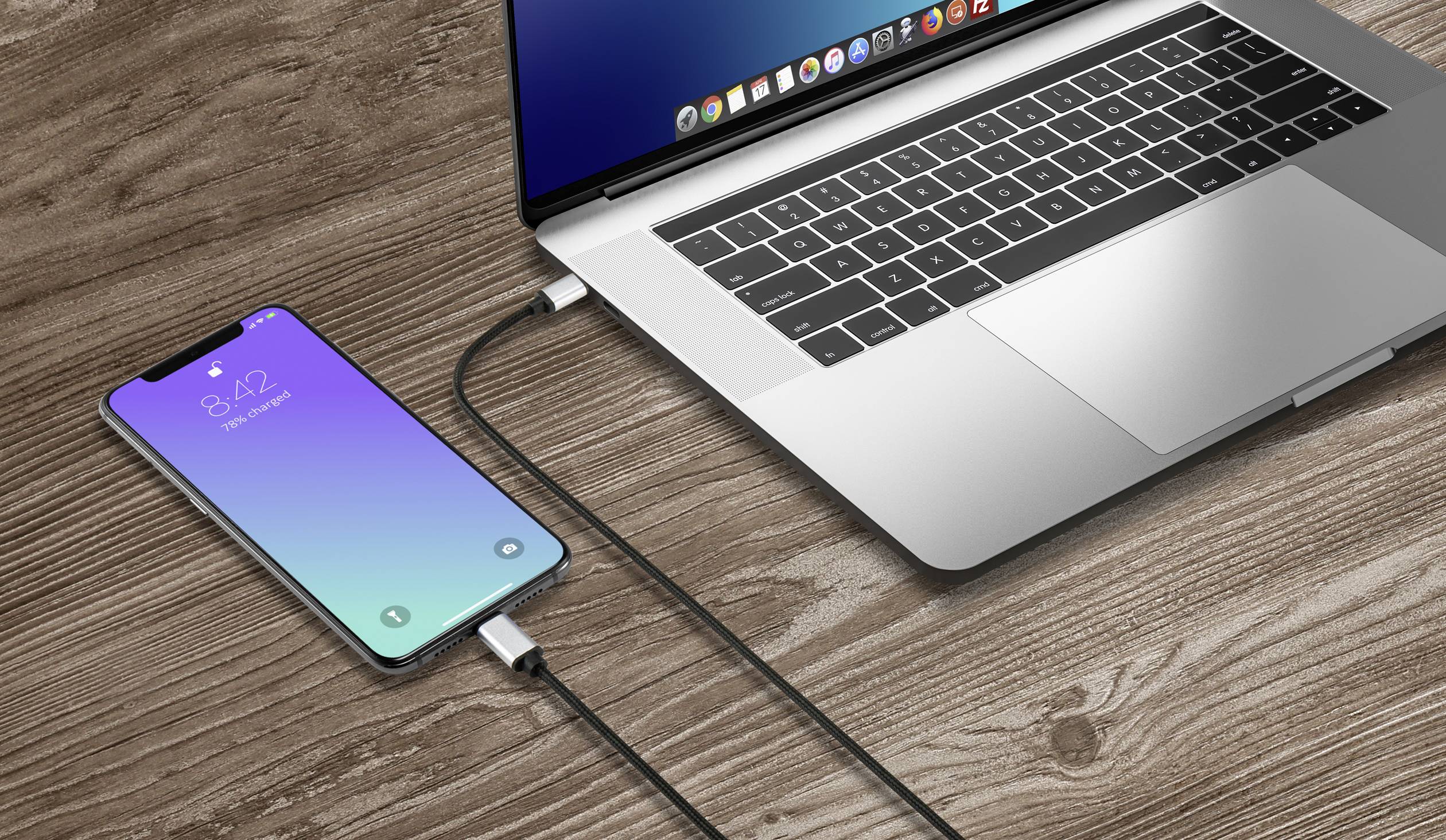 Ein Smartphone ist mit einem Kabel an einen Laptop angeschlossen, beide liegen auf einer Holzoberfläche. Das Smartphone zeigt 4:12 Uhr an.