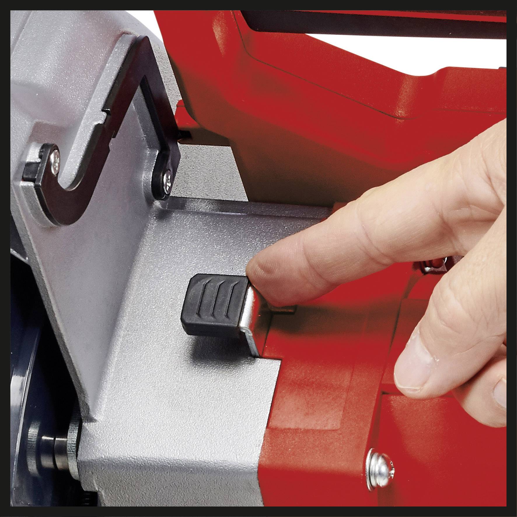 Ein Finger drückt einen roten Sicherheitsschalter an einer Metallmaschine, um sie zu aktivieren oder ausschalten.