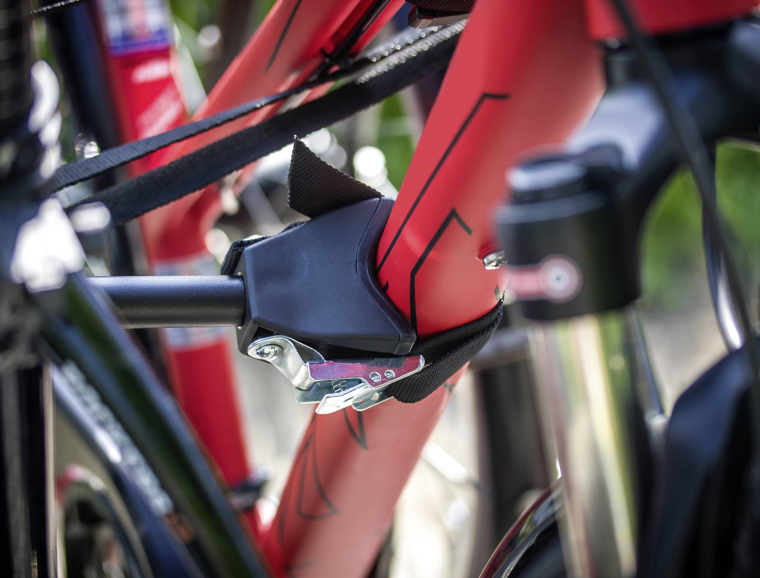 Fahrrad mit rotem Rahmen in Nahaufnahme, sicher mit einem schwarzen Schloss an einem weiteren Fahrrad befestigt.