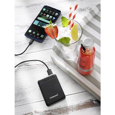 Smartphone lädt über Powerbank auf; daneben ein Getränk mit Erdbeeren und Minze auf einem Tablett.